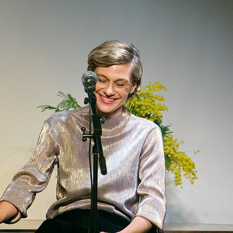 Artiste souriante au micro sur scène au Domaine de la Tour, Hérault, événement culturel