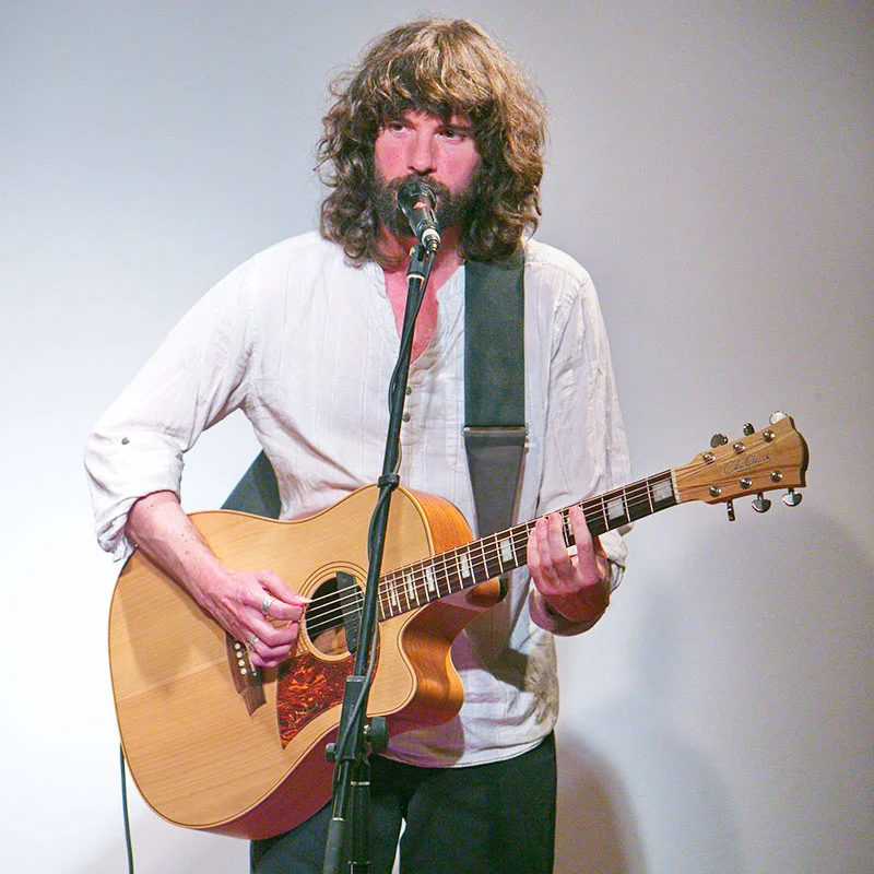 Chanteur guitariste barbu se produisant lors d'un événement au Domaine de la Tour, Hérault