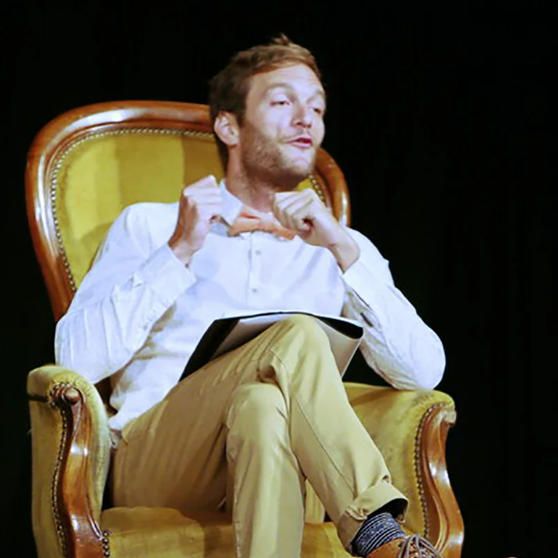 Comédien assis dans un fauteuil doré lors d'une lecture théâtrale au Domaine de la Tour en Hérault