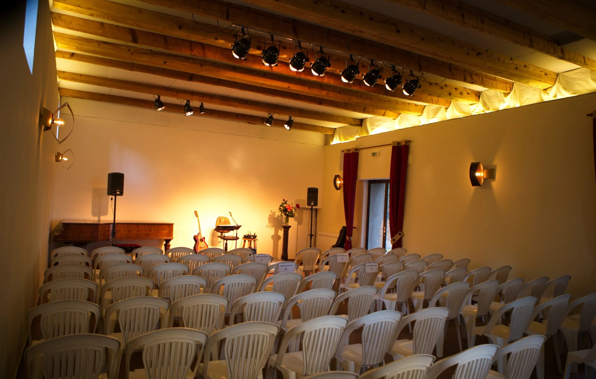 Salle de réception avec poutres en bois et éclairages scéniques au Domaine de la Tour, mariage Hérault