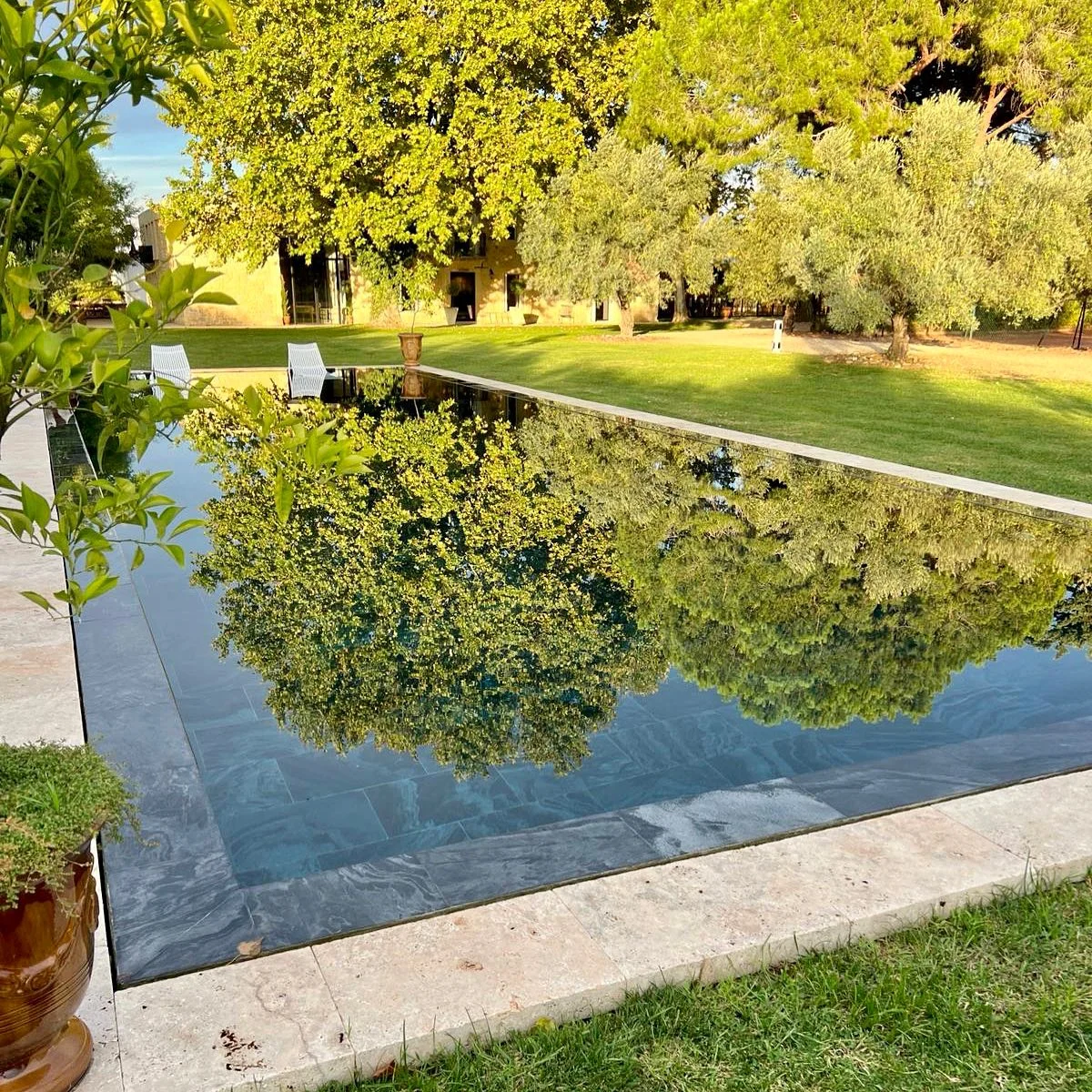 Miroir d'eau à fond noir reflétant le parc et la bastide du Domaine de la Trinité, Hérault