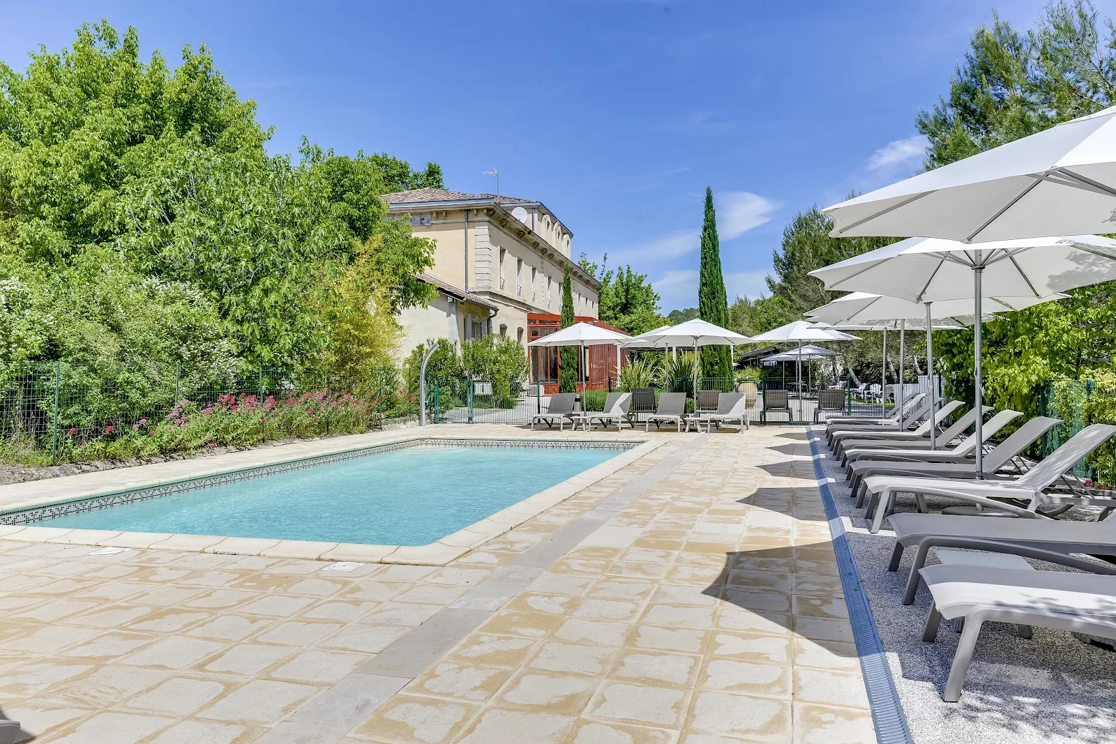 Piscine extérieure avec transats et parasols blancs au Domaine de l'Estelou - lieu de mariage Hérault