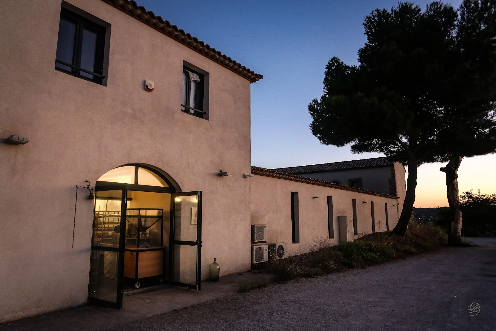 Façade du Domaine de Montmau au crépuscule, mas provençal blanc avec entrée voûtée éclairée et pin parasol, Hérault