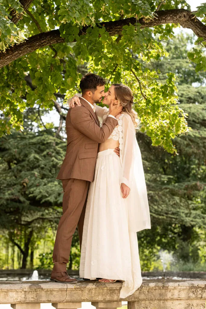 Couple marié s'embrassant, jardin verdoyant, balustrade pierre, ambiance romantique, Domaine de Rieucoulon Montpellier mariage Hérault Occitanie