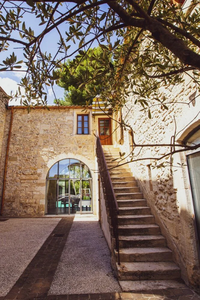 Cour intérieure du Domaine de Verchant avec escalier en pierre et grande baie vitrée arquée, mariage en Hérault