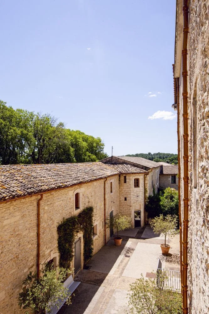 Cour intérieure en pierre calcaire du Domaine de Verchant avec végétation et bâtiments historiques, Hérault