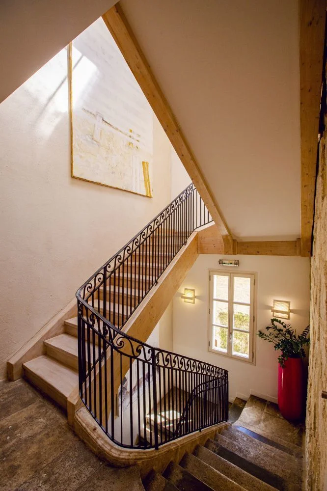Escalier intérieur en pierre avec rampe en fer forgé et poutres bois du Domaine de Verchant, Hérault