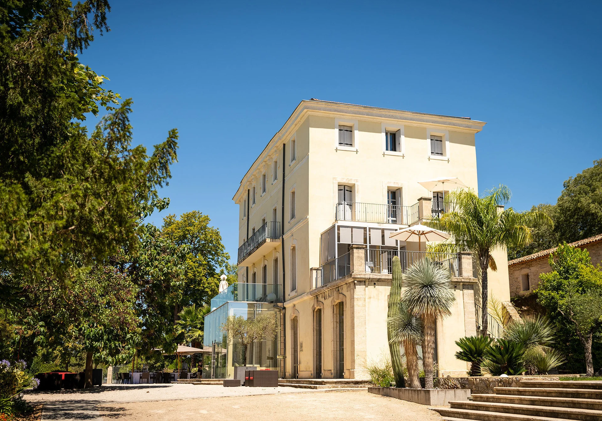Façade du château Domaine de Verchant entourée de palmiers et végétation méditerranéenne, mariage Hérault