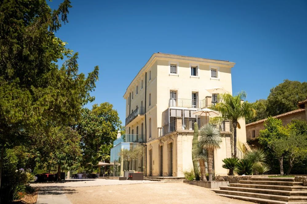 Façade du château Domaine de Verchant sous ciel bleu intense avec palmiers et cactus, mariage Hérault
