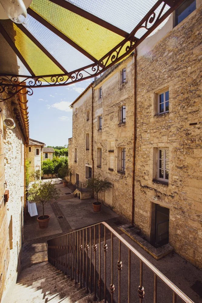 Vue depuis la mezzanine sur la cour intérieure en pierre du Domaine de Verchant avec vignes en fond, Hérault