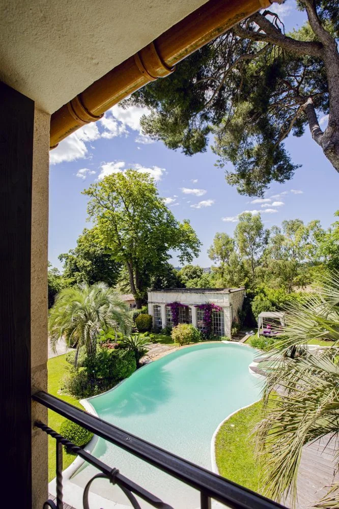Vue depuis le balcon sur la piscine et le jardin fleuri du Domaine de Verchant, lieu de mariage dans l'Hérault
