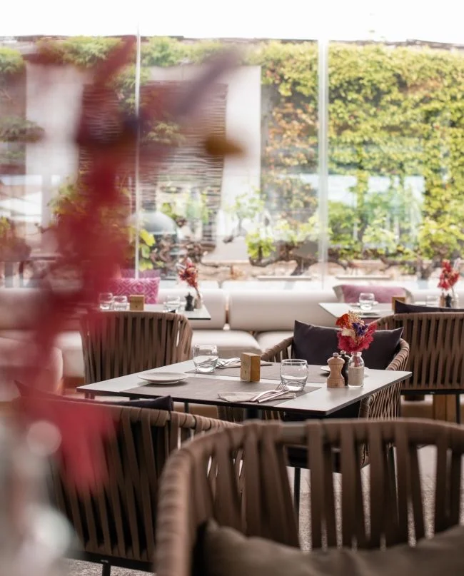 Salle de restaurant du Domaine de Verchant avec tables dressées et vue sur jardin, mariage Hérault