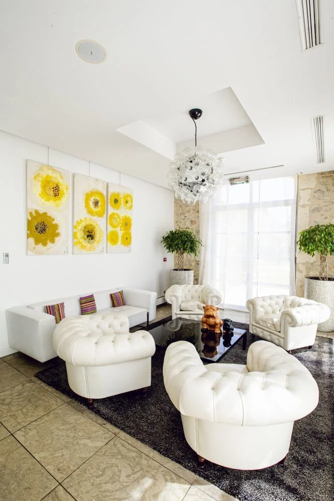 Salon lounge élégant du Domaine de Verchant avec canapés Chesterfield blancs et lustre design - lieu de mariage Hérault