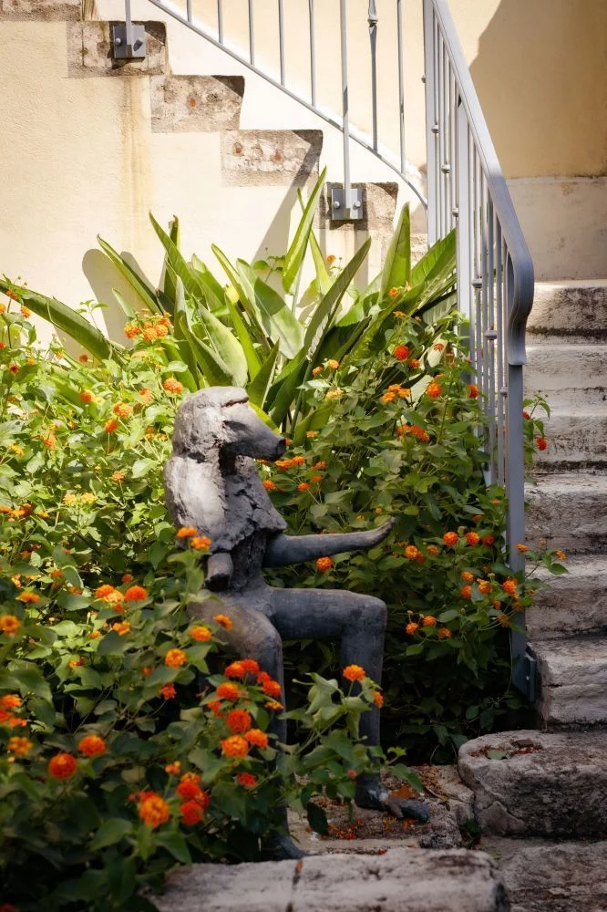 Sculpture artistique entourée de fleurs orangées dans le jardin du Domaine de Verchant, lieu de mariage en Hérault