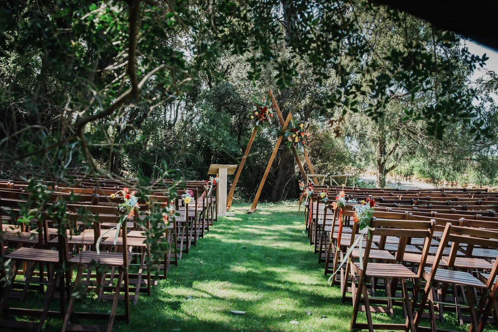 Cérémonie laïque extérieure Domaine des Hospitaliers Hérault avec arche bois et chaises sur pelouse