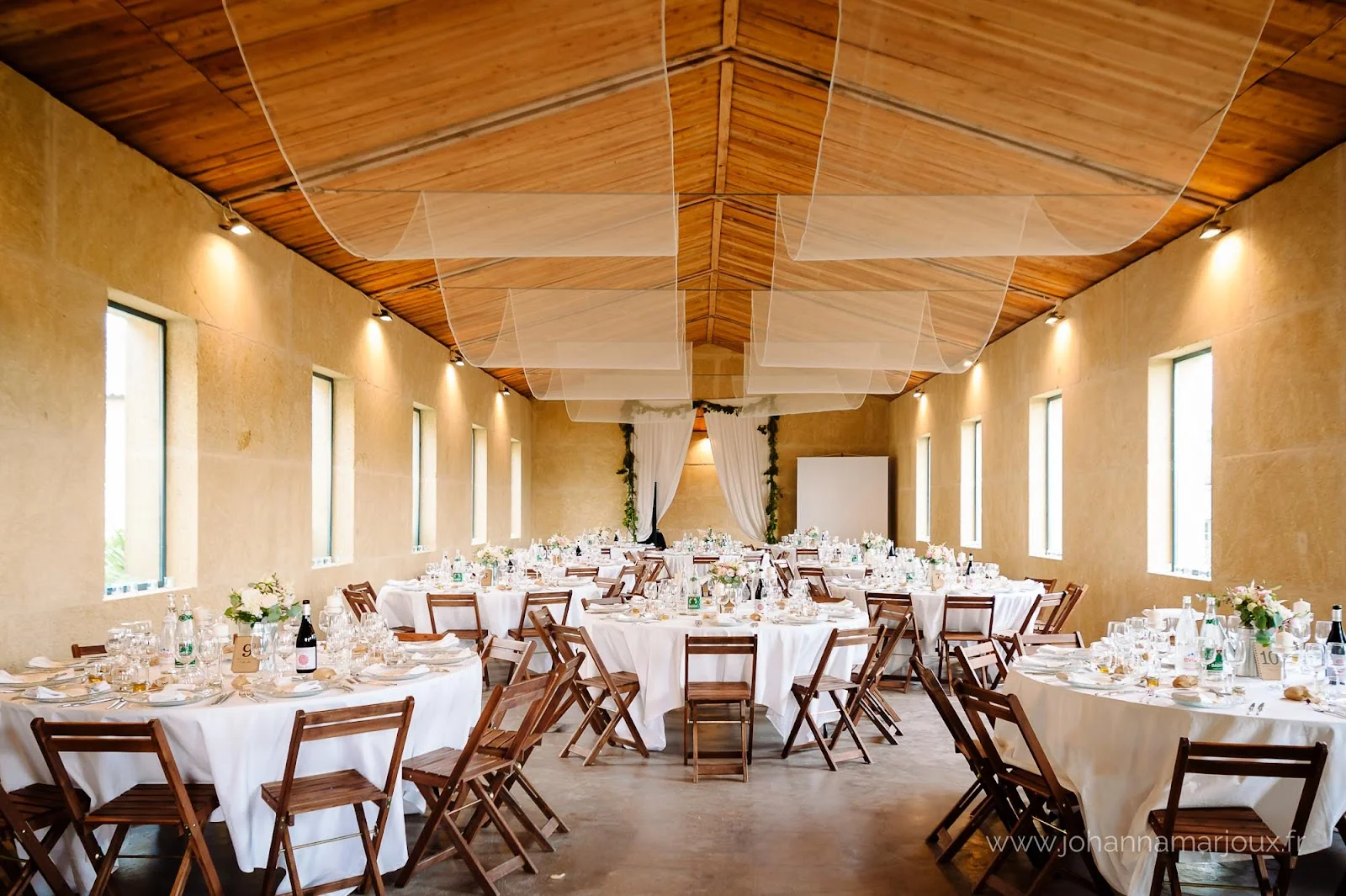 Salle de réception mariage Domaine des Hospitaliers Hérault avec tables rondes dressées et plafond en bois
