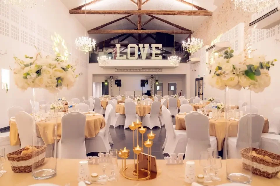 Salle de mariage Domaine des Laux Hérault décorée en blanc et or avec lustre cristal et lettres LOVE lumineuses