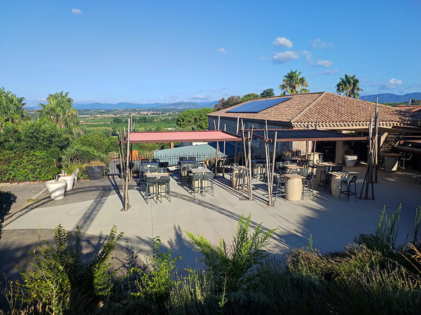 Terrasse panoramique du Domaine des Laux Hérault avec vue sur la plaine et les montagnes, espace cocktail en plein air