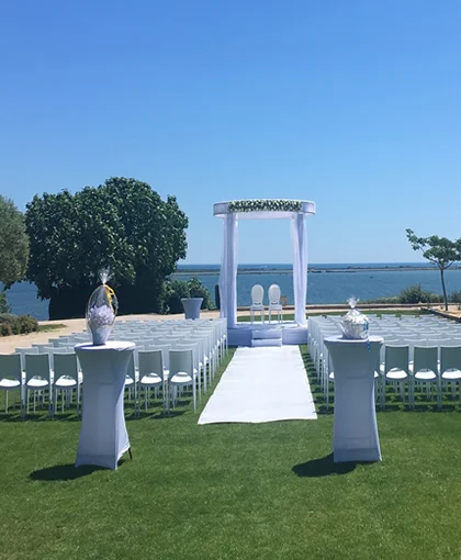 Arche de cérémonie drapée avec chaises médaillon et bouquets de roses blanches face à l'étang, Domaine des Moures Hérault