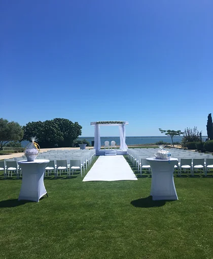 Cérémonie extérieure de mariage au Domaine des Moures avec arche fleurie blanche face à l'étang de Thau, Hérault