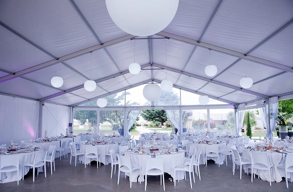 Salle de réception sous chapiteau au Domaine des Moures avec tables blanches et boules lumineuses, Hérault