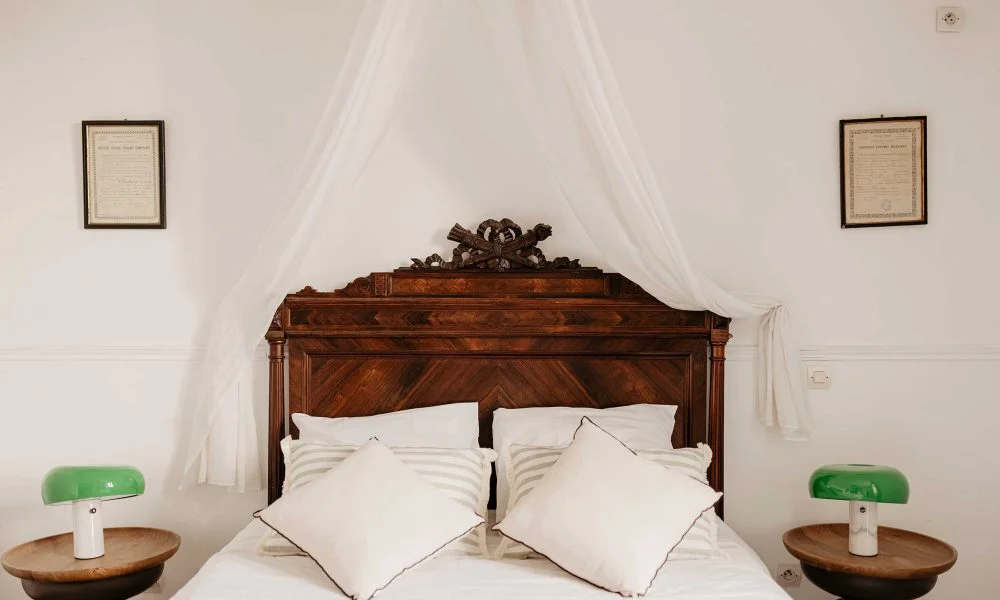 Chambre avec baldaquin et tête de lit en bois sculpté au Domaine des Rives, hébergement mariage Hérault