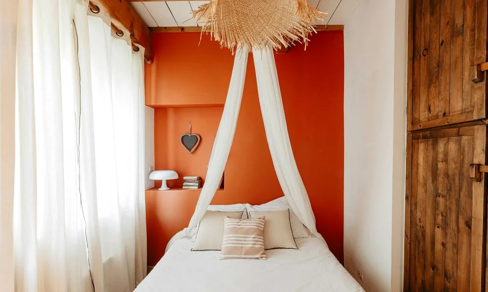 Chambre romantique baldaquin raphia et mur terracotta au Domaine des Rives Hérault mariage