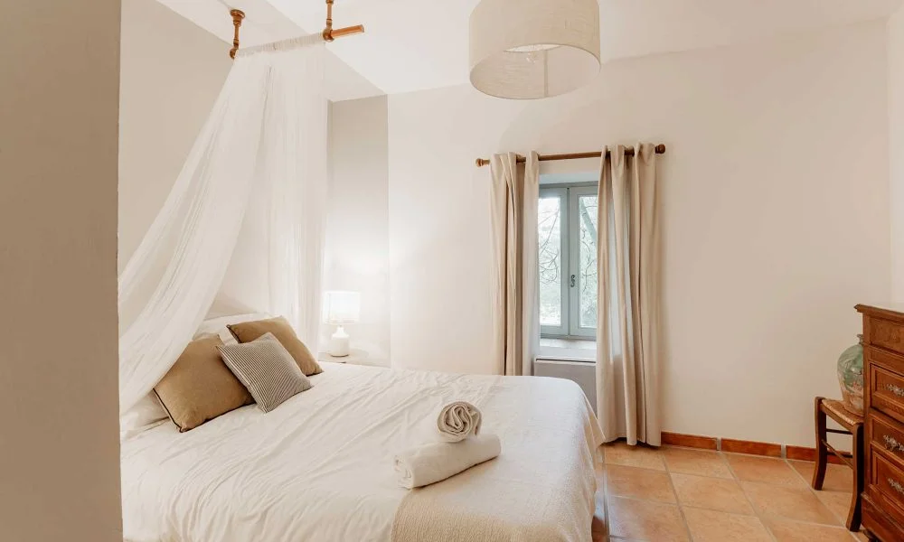 Chambre avec baldaquin blanc et tomettes au sol dans le gîte du Domaine des Rives, mariage Hérault