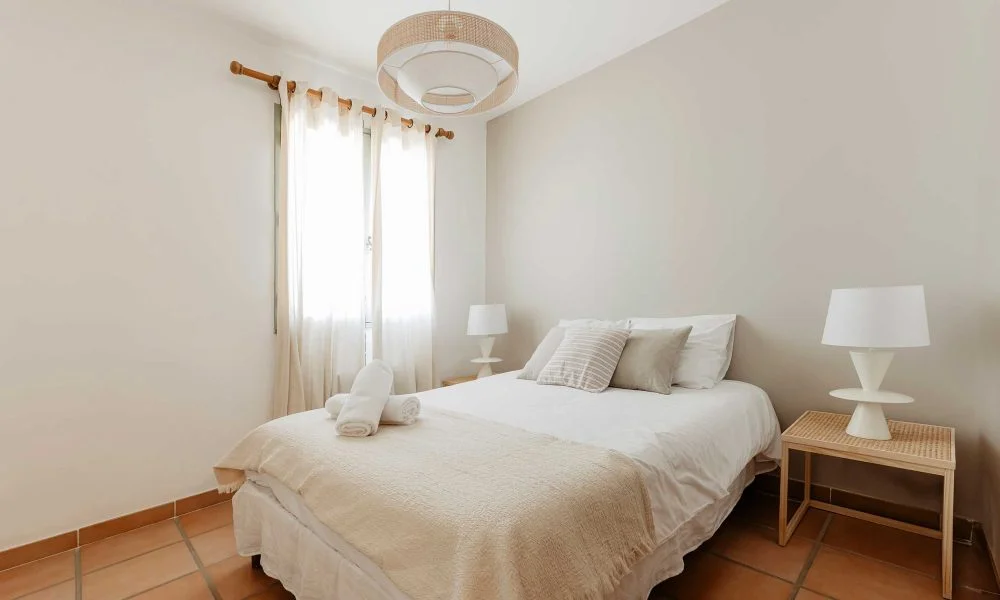Chambre double blanche avec lustre en rotin au Domaine des Rives Hérault mariage
