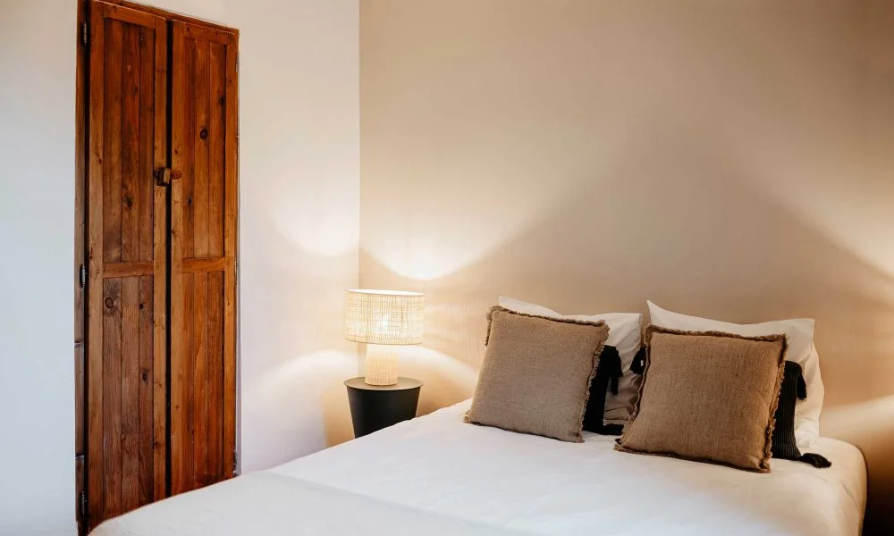 Chambre en lin naturel avec porte en bois ancien au Domaine des Rives, hébergement authentique Hérault