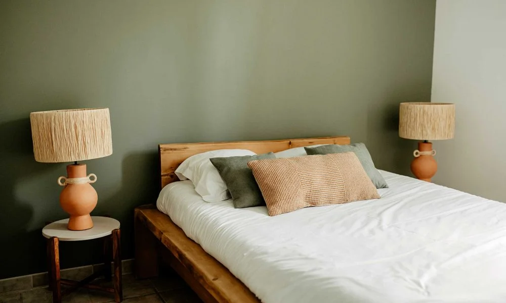 Chambre vert sauge avec lit en bois et lampes terracotta au Domaine des Rives, hébergement mariage Hérault