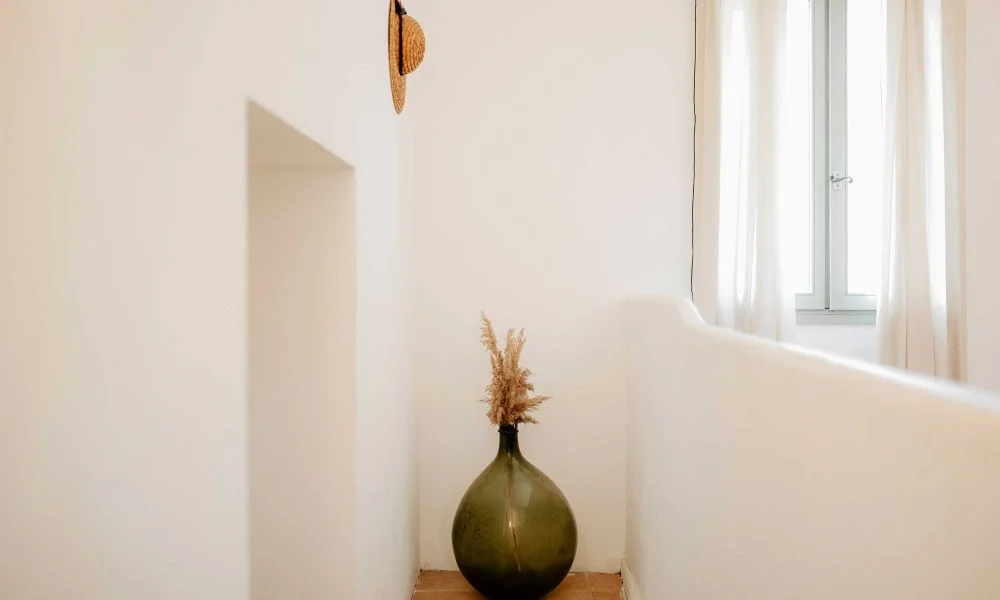 Couloir épuré avec grande dame-jeanne verte et niche murale au Domaine des Rives, décoration mariage Hérault