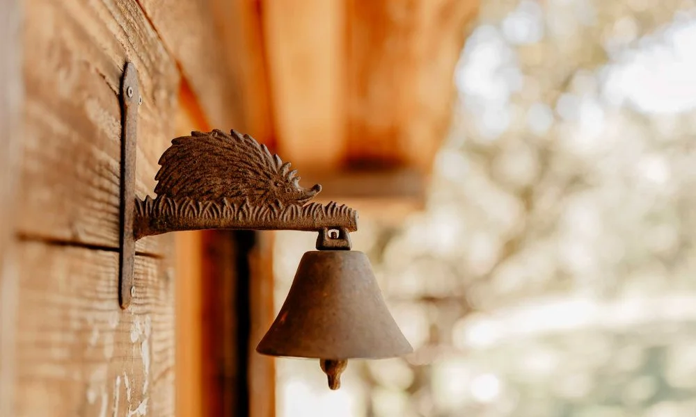 Cloche décorative en fonte rouillée en forme de hérisson sur mur bois au Domaine des Rives Hérault
