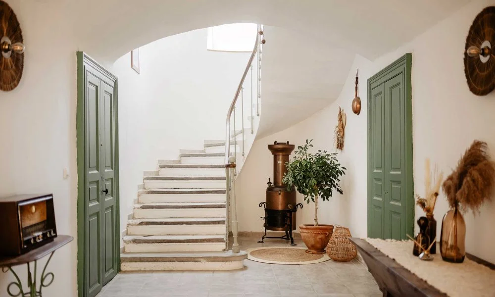 Hall d'entrée avec escalier en pierre et portes vertes au Domaine des Rives, mas provençal Hérault