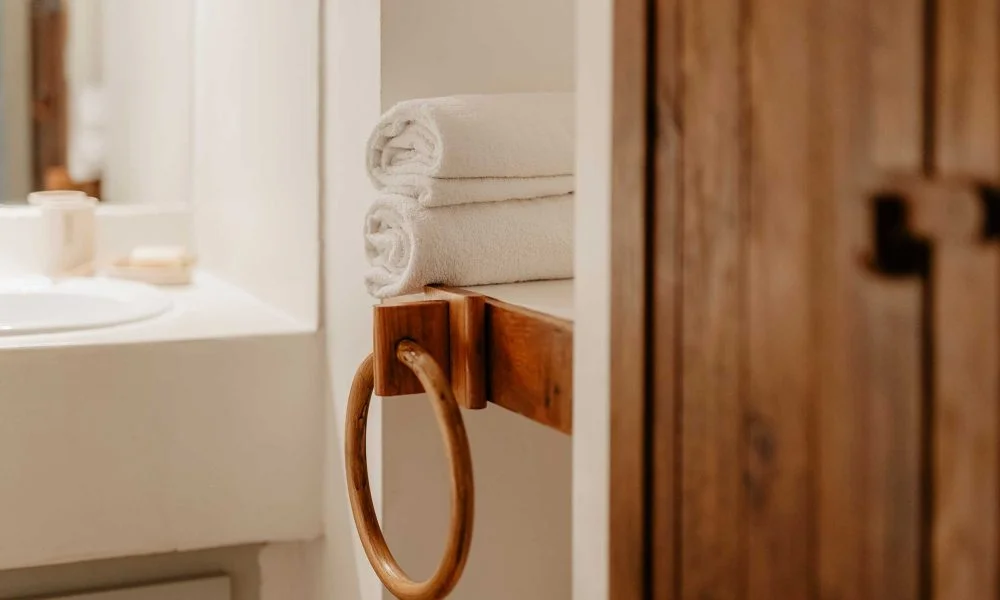 Détail salle de bain avec serviettes et porte-serviette bois au Domaine des Rives Hérault