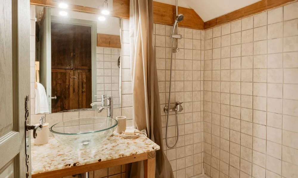 Salle de bain rustique avec vasque en verre et douche au Domaine des Rives, hébergement mariage Hérault