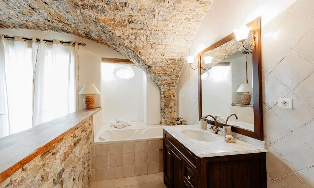 Salle de bain avec voûte en pierre et baignoire encastrée au Domaine des Rives, suite de luxe Hérault