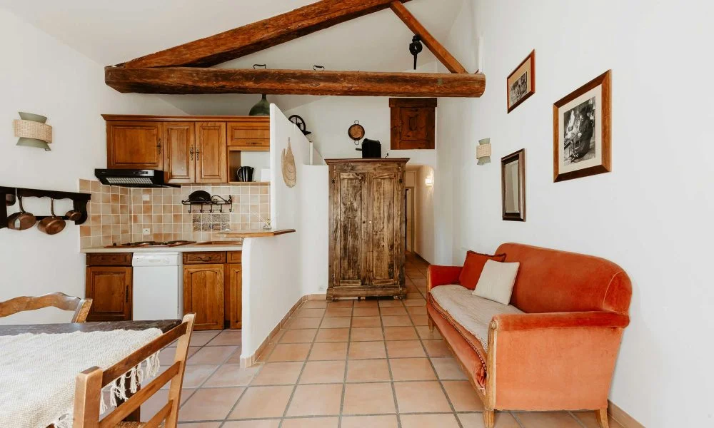 Séjour cuisine avec canapé velours orange et poutres au Domaine des Rives Hérault