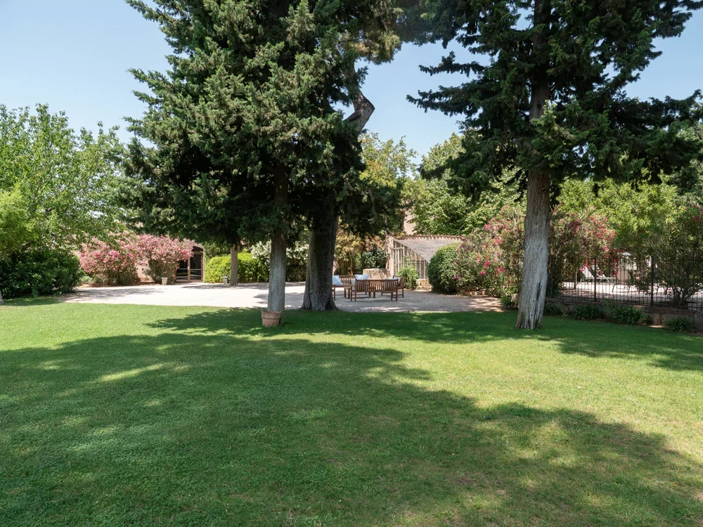 Jardin du Domaine Fon de Rey avec cyprès et bâtiment en pierre, lieu de mariage dans l'Hérault
