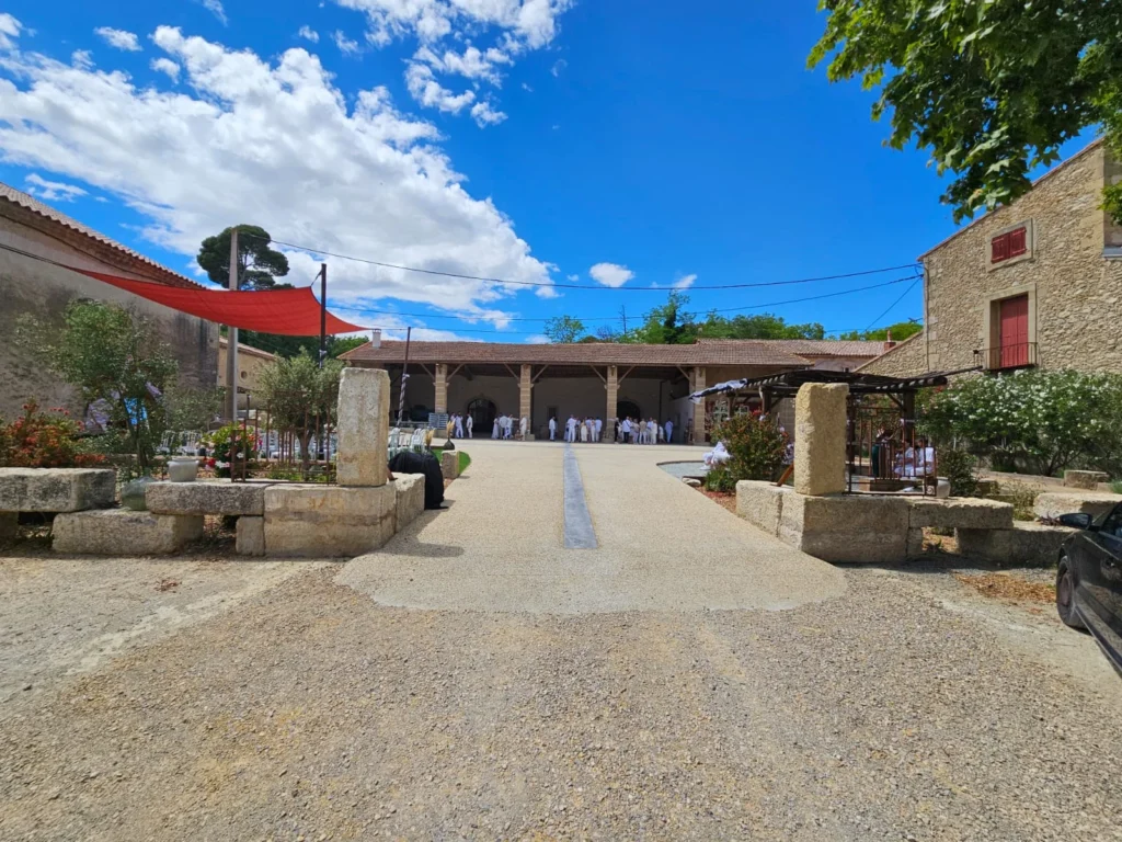 Cérémonie de mariage extérieure au Domaine Grande Canague en Hérault avec invités rassemblés sous le porche