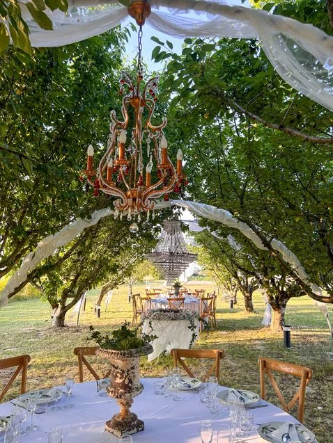 Lustre cuivré suspendu à une branche au-dessus des tables dressées dans le verger du Domaine La Fourcade