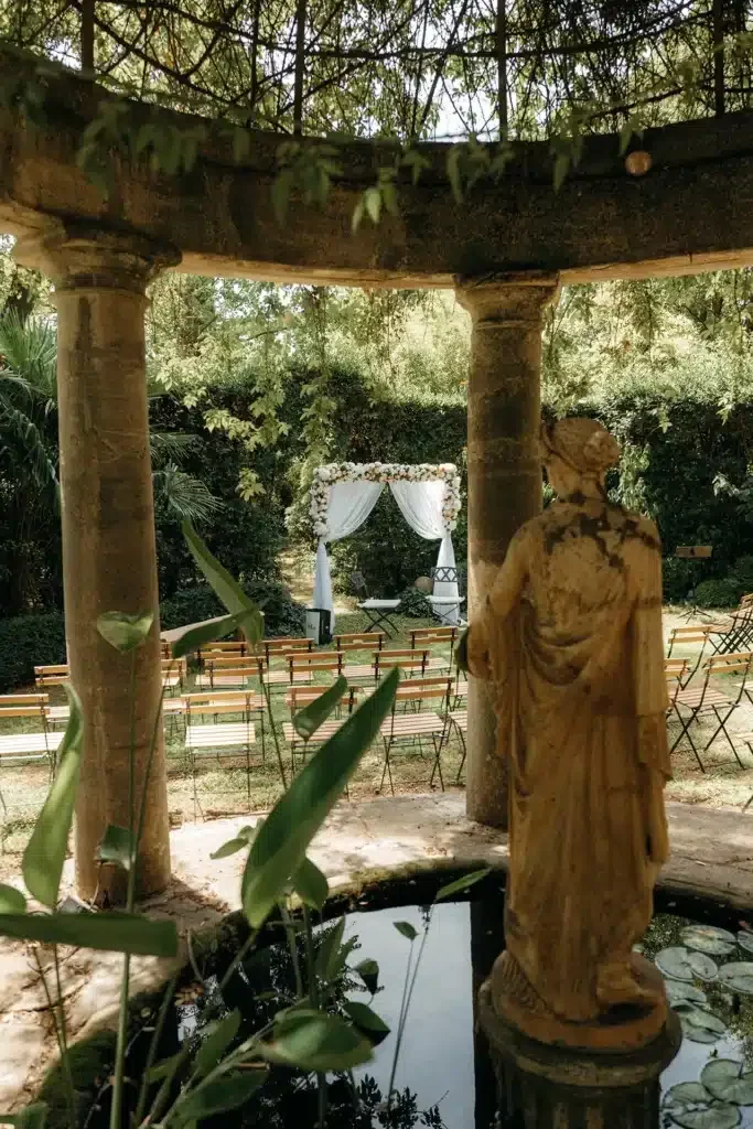 Vue large du kiosque en pierre, bassin nénuphars et arche de cérémonie au Domaine Le Petit Malherbes, Hérault