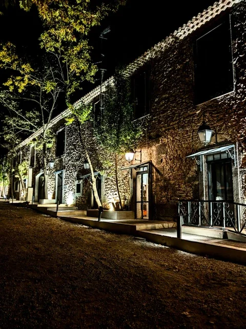 Façade en pierres illuminée la nuit avec lanternes et végétation au Domaine Les Barrettes Agde Hérault