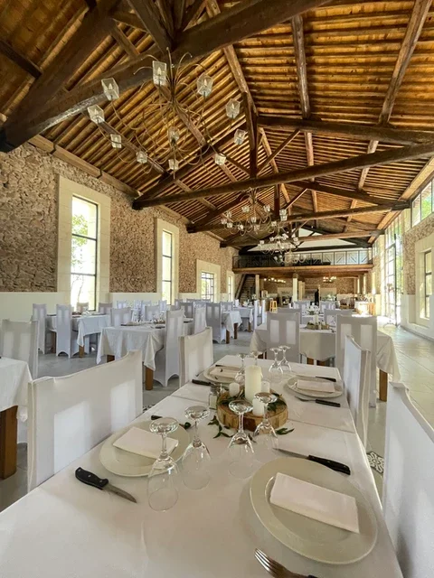 Salle de réception dressée pour mariage au Domaine Les Barrettes Agde, tables blanches et charpente bois Hérault