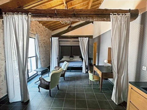 Suite avec lit baldaquin et murs en pierres au Domaine Les Barrettes Agde, hébergement mariage Hérault