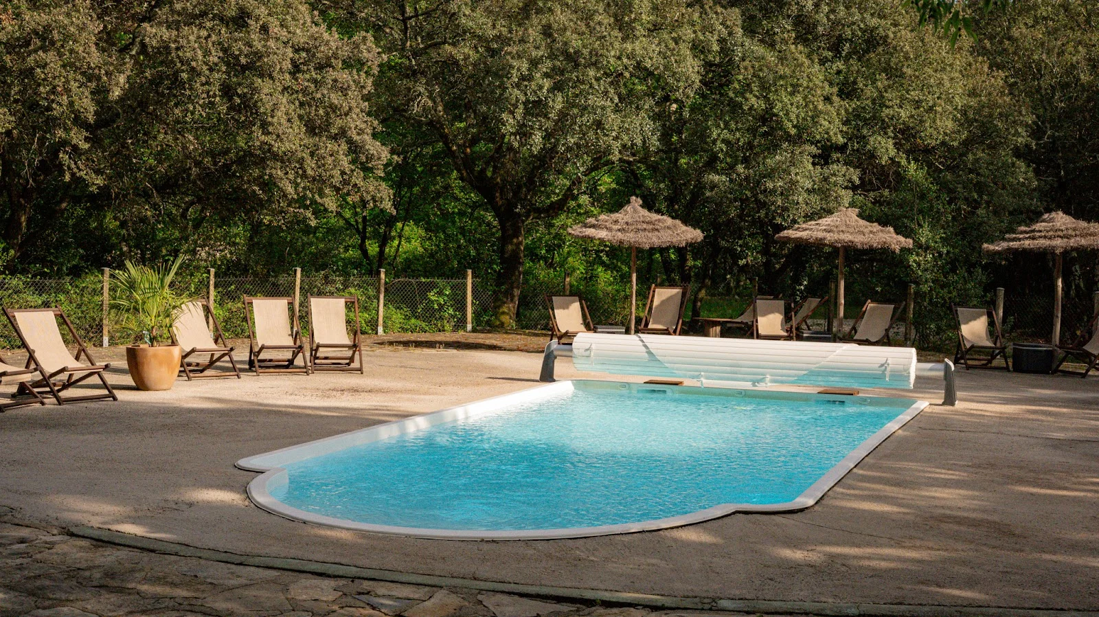 Piscine extérieure turquoise du Domaine du Mas de Coulet avec transats et parasols en chaume, mariage Hérault