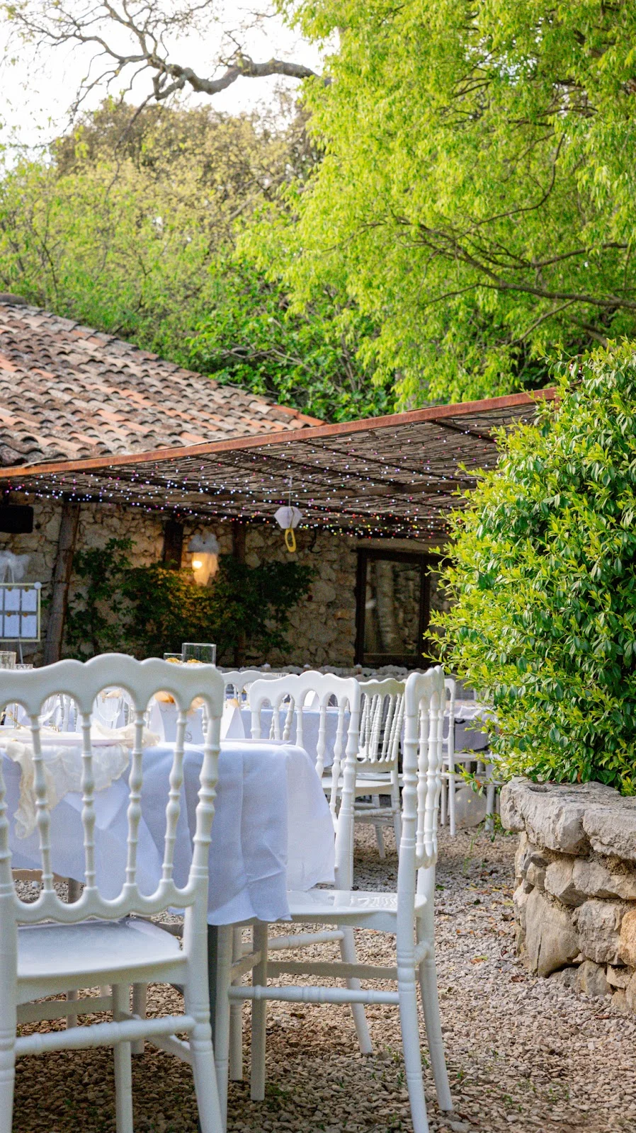 Réception extérieure avec tables rondes et chaises Napoléon blanches au Domaine du Mas de Coulet, mariage Hérault