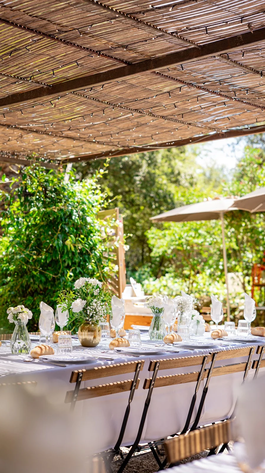 Table de réception dressée sous pergola en bambou avec fleurs blanches au Domaine du Mas de Coulet, mariage Hérault