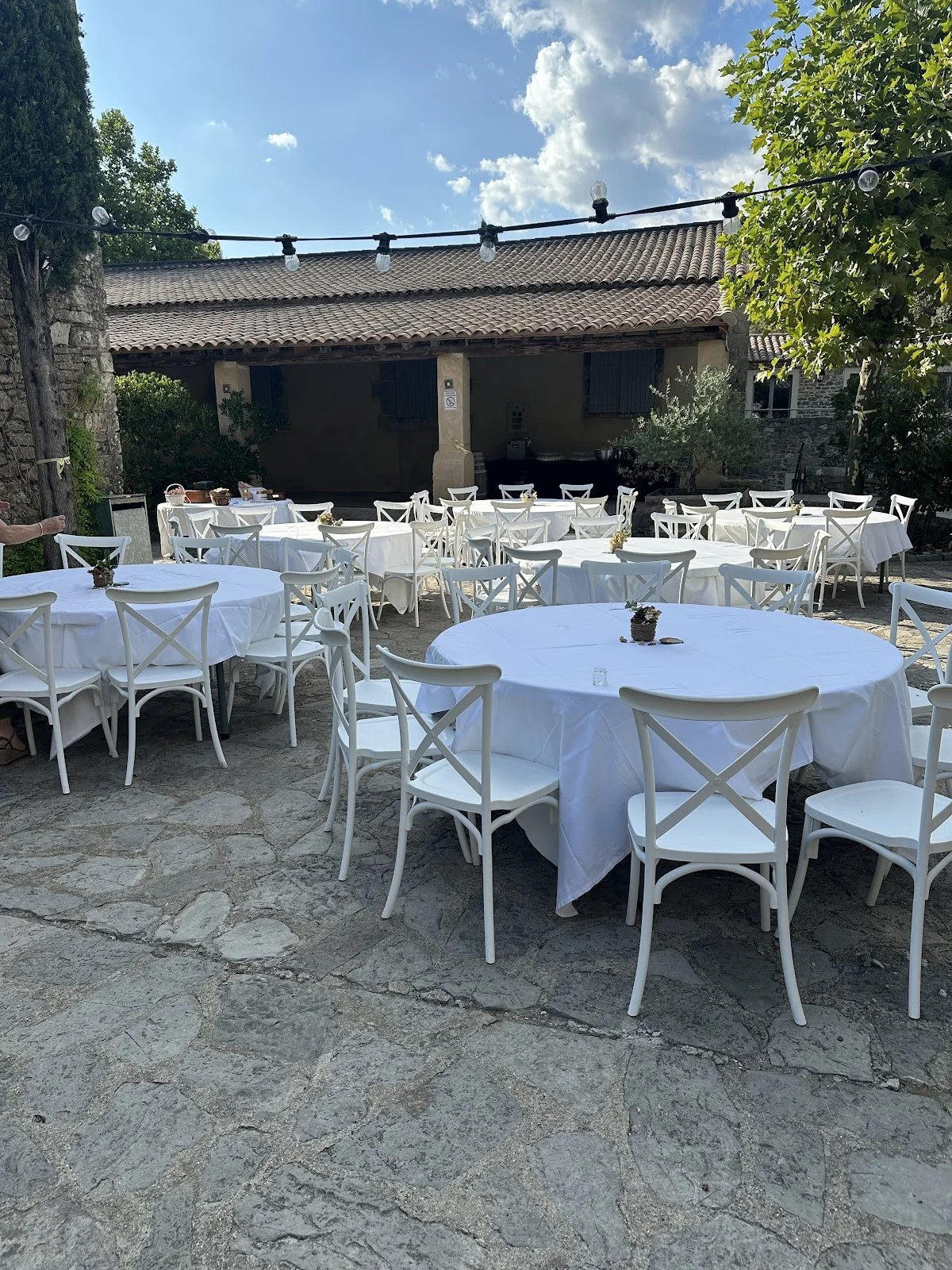 Réception de mariage en plein air au Domaine Mas de Martin, tables et chaises blanches dans la cour en pierre, Hérault