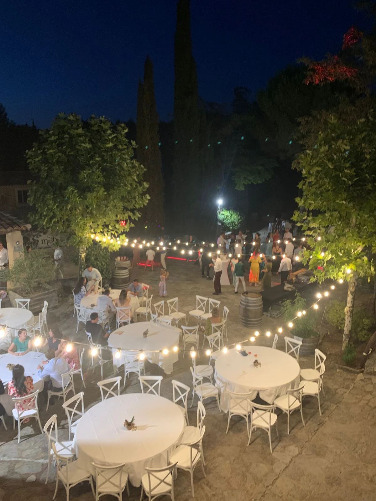 Soirée de mariage au Domaine Mas de Martin, cour illuminée par des guirlandes avec invités et tables blanches, Hérault